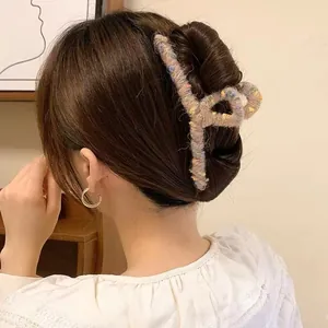 Tweed knit hair claw clip and gold hoop earrings styled on a woman in a cozy home setting
