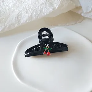 Detailansicht einer glänzend schwarzen Haarklammer mit einem Kirsch-Anhänger