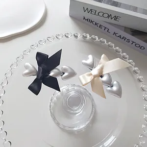 Detail of silk bow hair clips with silver pearl heart elements on a glass tray