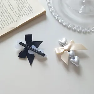 Elegant ribbon bow hair clips with heart charms in black and beige satin finish