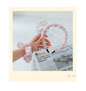 Detail van roze geruite stoffen haarband en bijpassende scrunchie op decoratieve achtergrond