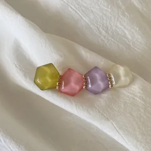 Pastel geometric crystal hair clip with frosted beads and gold rings on white fabric