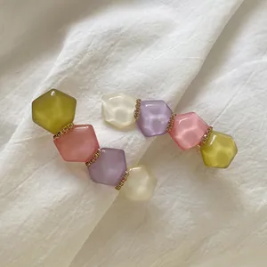 Close-up of geometric pastel crystal hair clips with resin hexagons and gold accents