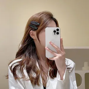 Paire de barrettes géométriques noir mat portées sur le côté pour coiffure cheveux ondulés