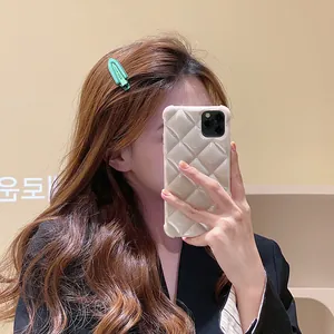 Détail d'une barrette géométrique vert menthe sur cheveux ondulés avec coque de téléphone
