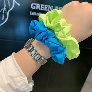 Close-up of bright blue and neon green fabric scrunchies worn on the wrist with a watch