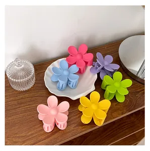 Macro-opname van zes matte, snoepkleurige bloemhaarklemmen op een houten tafelblad