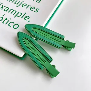 Détail de pinces à cheveux vertes sans couture avec texture cuir sur livre blanc