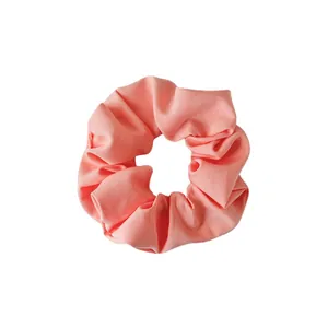 Solid peach pink fabric scrunchie with soft ruffled texture for daily hair styling