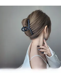 Pince à cheveux noire mate minimaliste utilisée pour un chignon élégant de femme