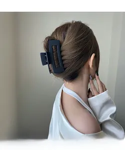 Grande pince à cheveux noire mate fixant un chignon pour un look élégant et minimal