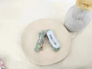 Detail view of handmade knitted hair clip with colorful stitching and metal duckbill clip