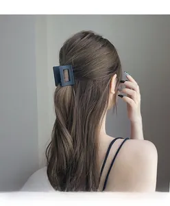 Détail d'une pince à cheveux carrée noire mate fixant une coiffure sur cheveux longs