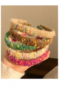 Close-up of colorful wool headbands with textured knit fabric held in hand