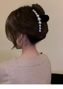 Detail view of a black hair claw clip with gradient pearls on an elegant updo