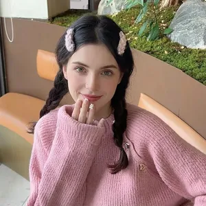 Girl wearing light pink plush hair clips and cozy knit sweater in a natural outdoor setting