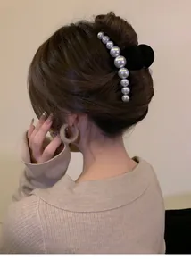 Detail of large black velvet hair claw clip with elegant white pearls on female model