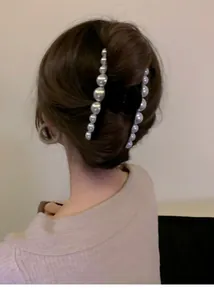 Detail of a black velvet hair claw with white pearls holding long hair in an elegant bun