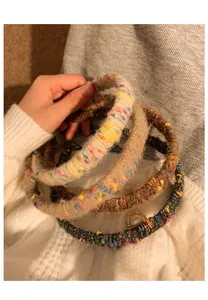 Detail of knitted wide headbands with mixed colorful yarn and elegant faux pearl accent
