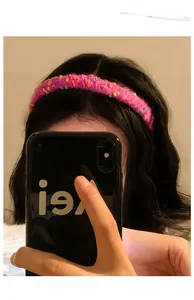 Close-up of a pink plush knitted headband with colorful flecks worn by a model