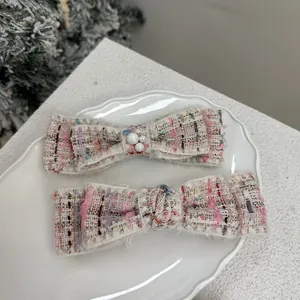 Pink French tweed bow hair clips with pearls on a decorative white ceramic plate