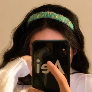 Green knit headband with colorful plush dots shown in a mirror selfie for hair styling