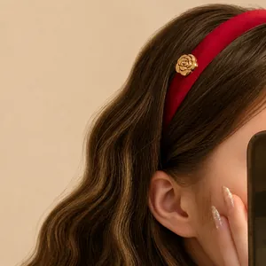 Serre-tête élégant en velours rouge avec fleur de camélia dorée sur modèle