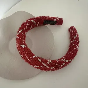 Macro detail of red tweed headband with silver metallic threads and handmade label