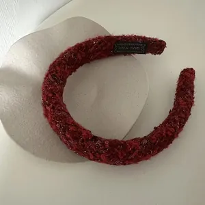 Detailed view of burgundy plush headband texture with handmade gold letter label