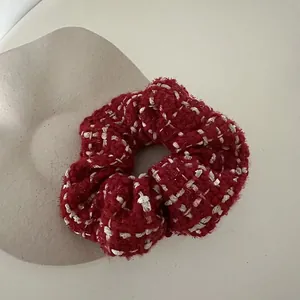 Close-up of red and white tweed scrunchie with woven texture for autumn hair styling