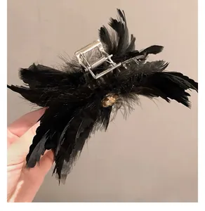 Détail d'une pince à cheveux en plumes noires avec strass champagne et attache métallique