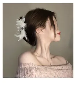 Gros plan sur une pince à cheveux élégante en plumes blanches avec strass pour femme