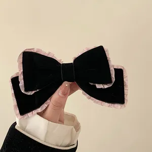 Detail of velvet bow hair clip featuring pink tulle ruffle trim held by a hand