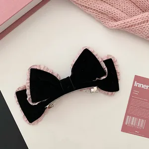 Close-up of black velvet bow hair clip with pink pleated lace and silver metal spring fastener