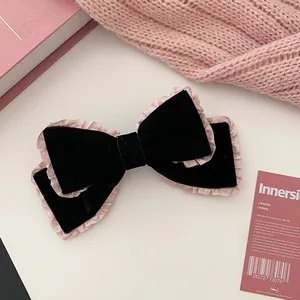Close-up of black velvet handmade bow hair clip with pink silk lace trim detail