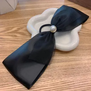French retro black satin mesh bow hair tie with large white pearl on white ceramic dish