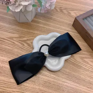 French vintage black satin bow scrunchie with a large pearl accent on a decorative tray