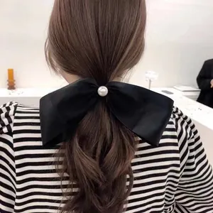 French vintage black satin bow hair tie with large pearl accent on a low ponytail
