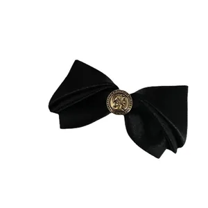 Oversized black satin bow hair clip with vintage Alexander Magnus bronze relief button