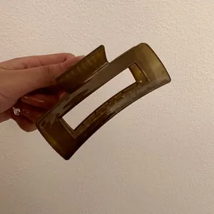 Detailweergave van een rechthoekige amberkleurige haarklem voor dikke haarstijlen