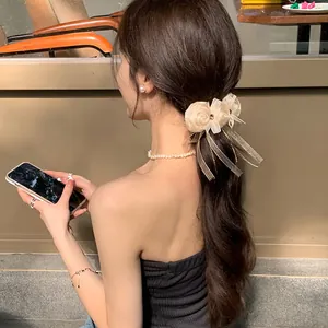Close-up of champagne silk rose hair tie with ribbons worn in a cozy cafe setting