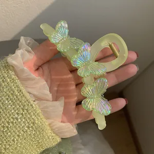 Grande pince à cheveux papillon jaune citron pour femme tenue sur un pull en tweed vert