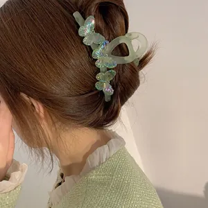 Grande pince à cheveux verte élégante avec papillons irisés portée par un modèle