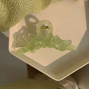 Détail macro d'une pince à cheveux vert clair avec des papillons 3D irisés