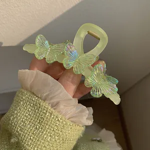 Détail d'une pince à cheveux vert clair ornée de papillons aux reflets irisés
