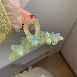 Gros plan d'une pince à cheveux mate verte avec papillons laser irisés décoratifs