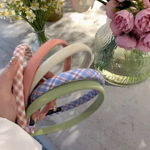Detail of five handmade fabric headbands with plaid and solid patterns in pastel colors