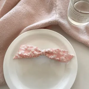 Detail of pink lace bow hair clip with white flower patterns on white ceramic plate