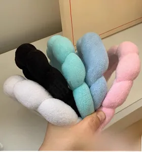 Close-up of five colorful plush sponge headbands in white black blue pink and green