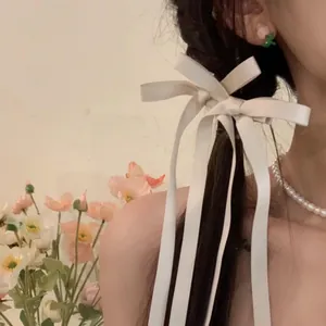 Elegant white satin bow hair clip with long ribbons on braided hair style